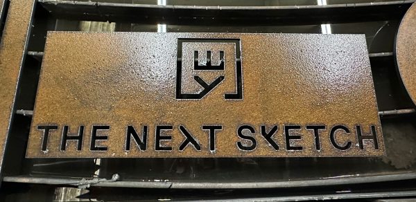 The Next Sketch logo cut into rusty metal