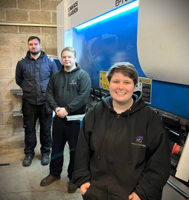 Three people stood in front of a folding machine